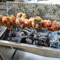 Skewer of food being grilled over a metal grid