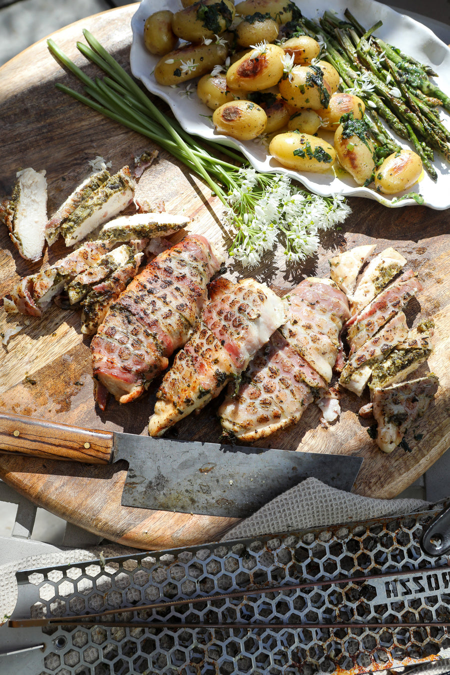 chicken breasts cooked with Rozza attachment surrounded by wild garlic and roasted potatoes and asparagus in outdoor sunny setting