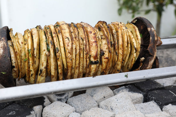 Rotating skewer of grilled food on a charcole grill