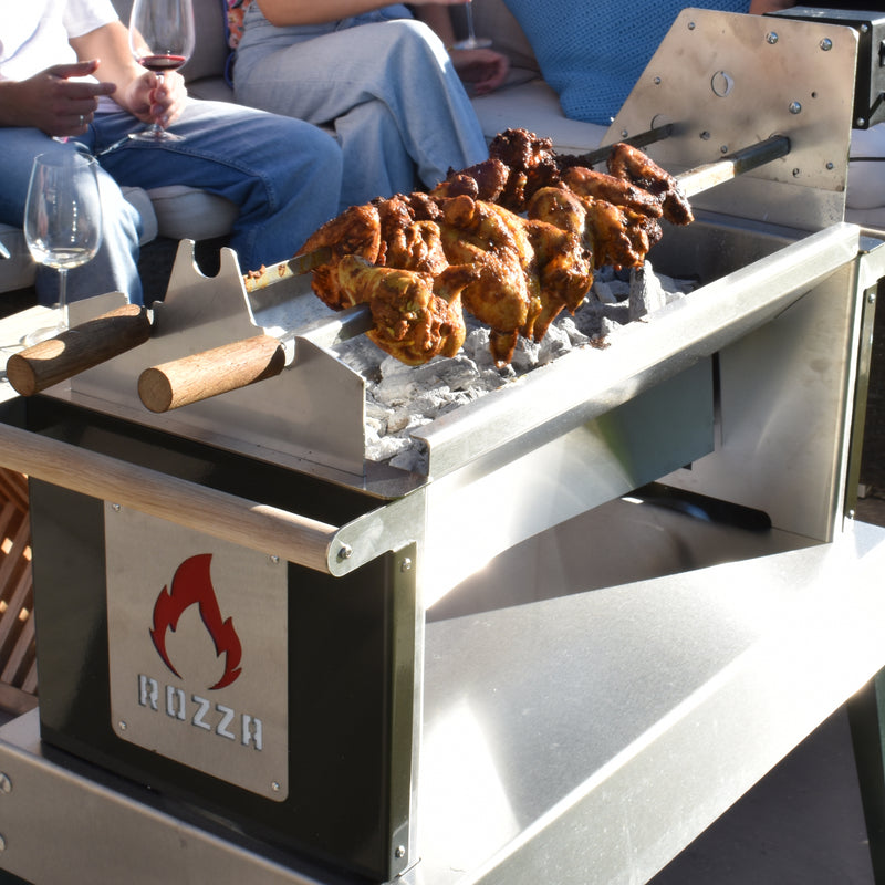 Grilled chicken on a Rozza grill with people sitting around, enjoying wine.