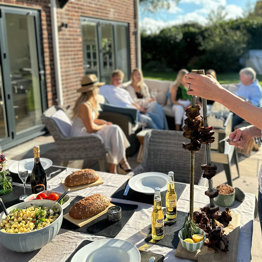 Outdoor gathering with people sitting on a patio, enjoying food and drinks.