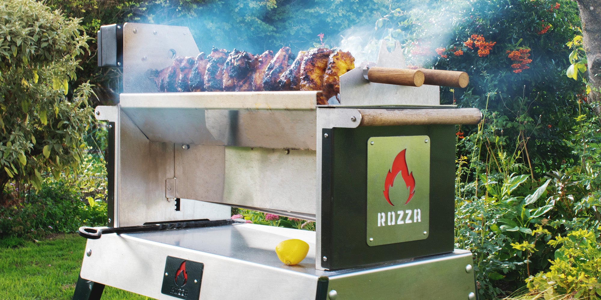 Grill with food cooking outdoors in a garden setting, featuring the Rozza brand.