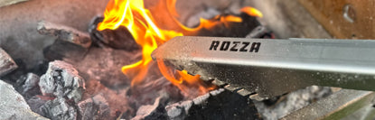 Rozza tongs over a fire with visible branding