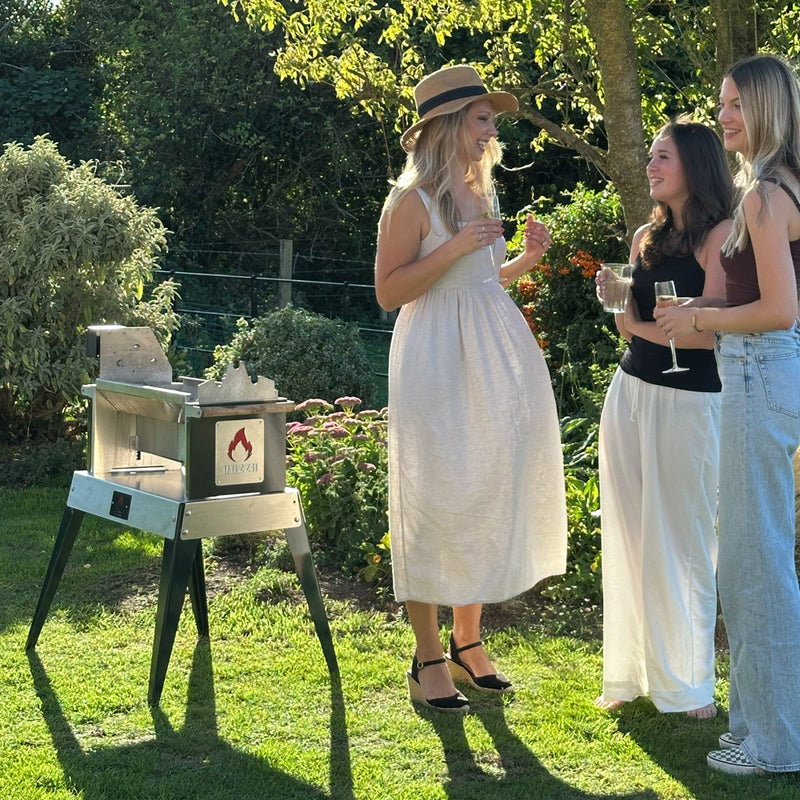 Three women standing outdoors near the Rozza in a garden setting
