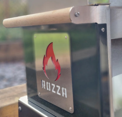 Metallic grill with 'Rozza' branding and flame logo on a blurred outdoor background